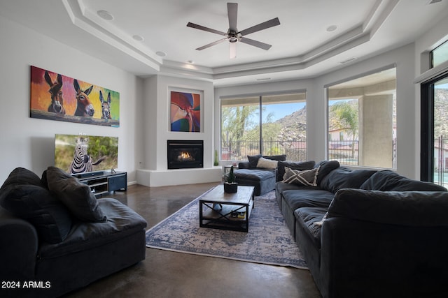 living room featuring a raised ceiling and ceiling fan