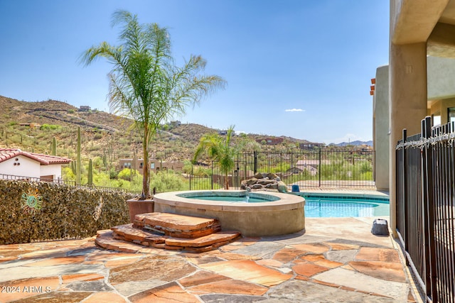 view of swimming pool featuring a patio, a mountain view, and an in ground hot tub