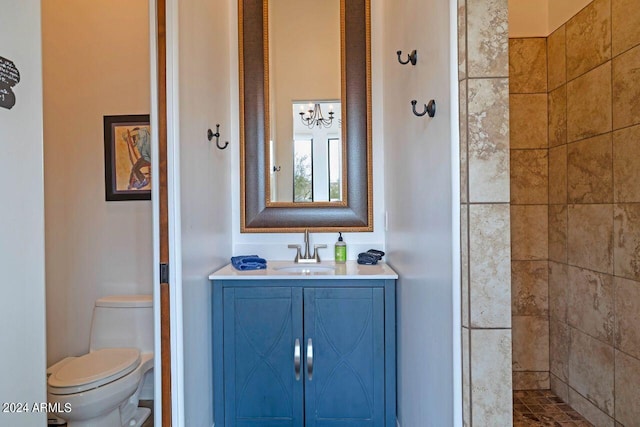 bathroom with tiled shower, toilet, and vanity