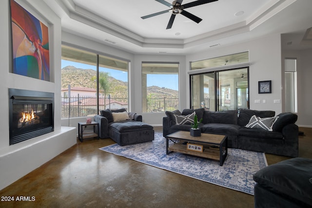 living room featuring a tray ceiling, ceiling fan, plenty of natural light, and a mountain view