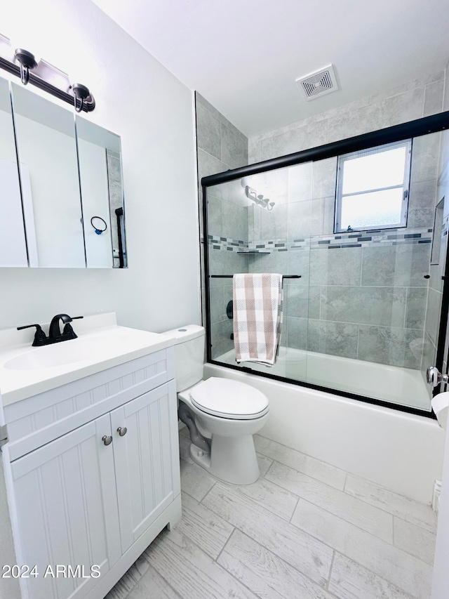 full bathroom featuring shower / bath combination with glass door, vanity, and toilet