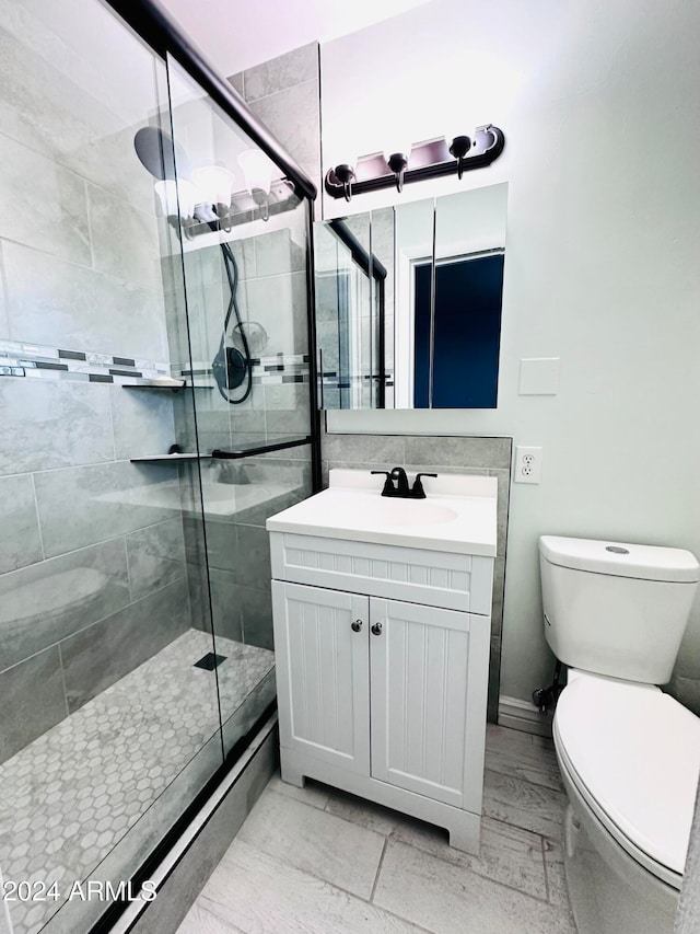 bathroom featuring vanity, toilet, and a shower with door