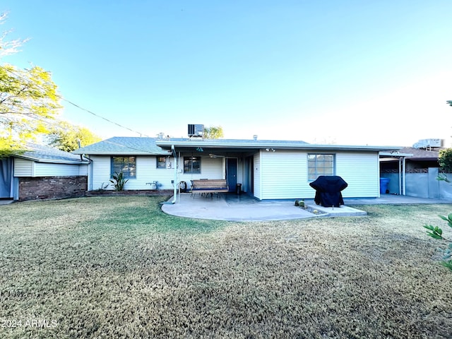 rear view of property featuring a lawn, a patio area, and cooling unit