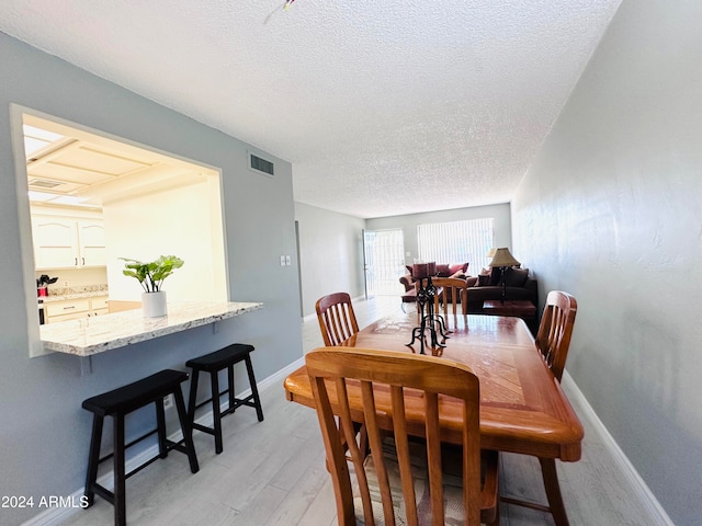 dining area with light hardwood / wood-style floors and a textured ceiling