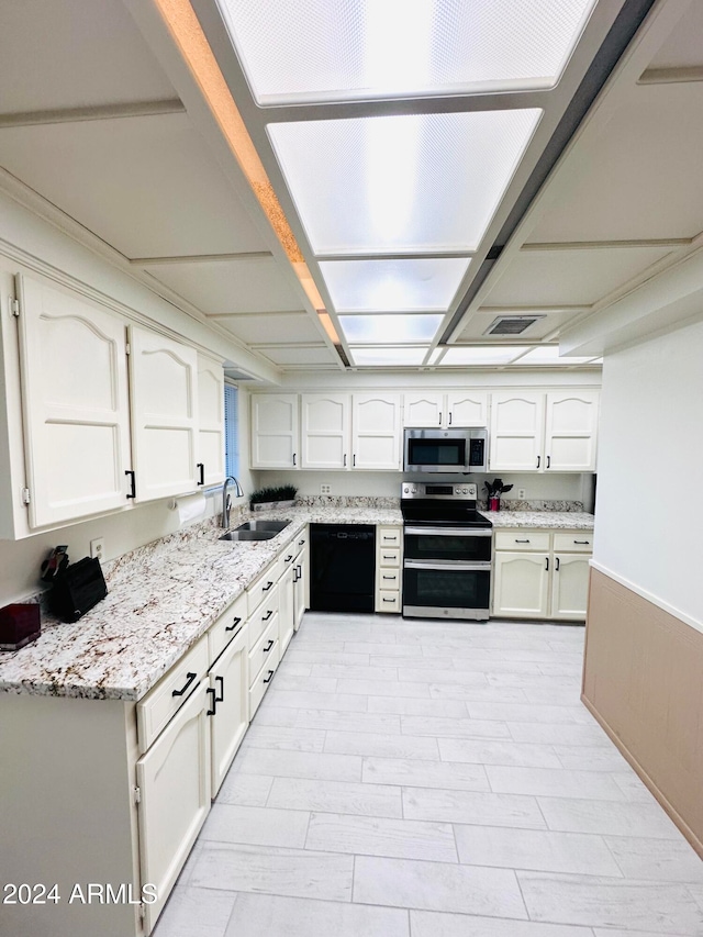 kitchen with light stone countertops, sink, white cabinets, and stainless steel appliances