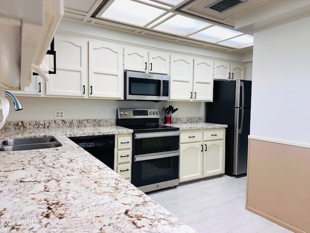 kitchen featuring white cabinetry, sink, stainless steel appliances, and light wood-type flooring