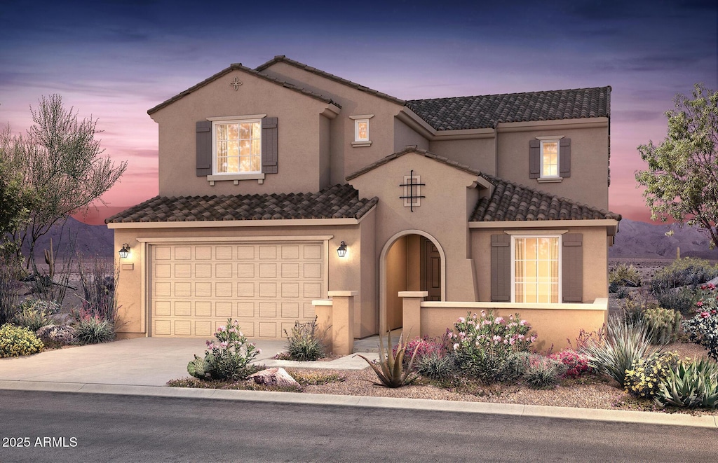 mediterranean / spanish-style home with an attached garage, concrete driveway, stucco siding, and a tile roof