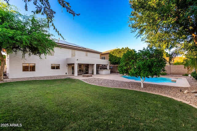 7247 W Buckskin Trl, Peoria, AZ 85383 - back of property with stucco siding, a fenced backyard, roof mounted solar panels, a patio, and exterior kitchen