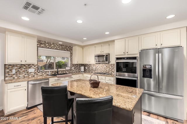 7247 W Buckskin Trl, Peoria, AZ 85383 - kitchen featuring stainless steel appliances, light wood-style flooring, a kitchen island, recessed lighting, and light stone countertops