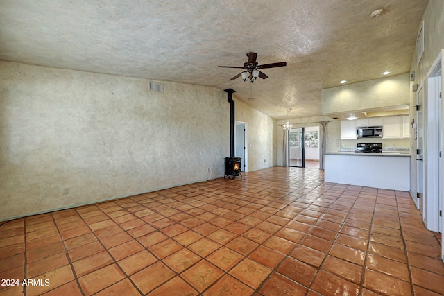 unfurnished living room with a wood stove, high vaulted ceiling, tile flooring, and ceiling fan