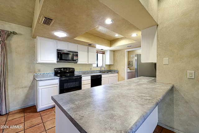 kitchen featuring white cabinets, kitchen peninsula, a tray ceiling, and black appliances