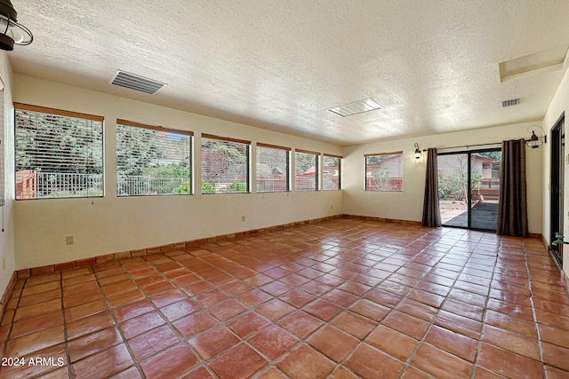 spare room featuring tile floors, a wealth of natural light, and a textured ceiling