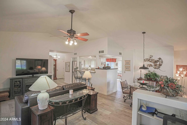 living room featuring ceiling fan with notable chandelier, vaulted ceiling, and light hardwood / wood-style flooring