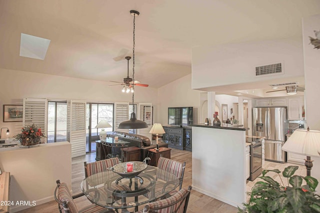 dining room with ceiling fan, light hardwood / wood-style flooring, and high vaulted ceiling