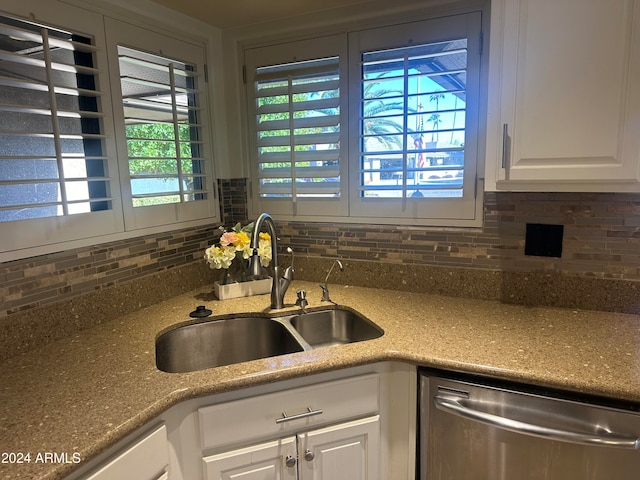 kitchen with backsplash, white cabinetry, sink, and stainless steel dishwasher