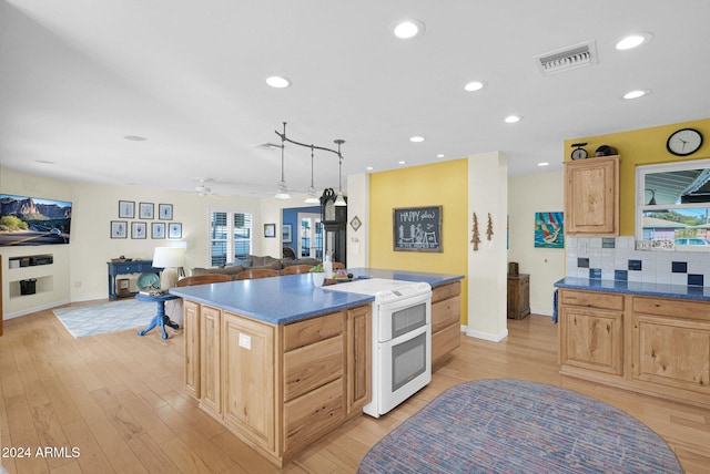 kitchen with ceiling fan, a healthy amount of sunlight, light brown cabinetry, a kitchen island, and range