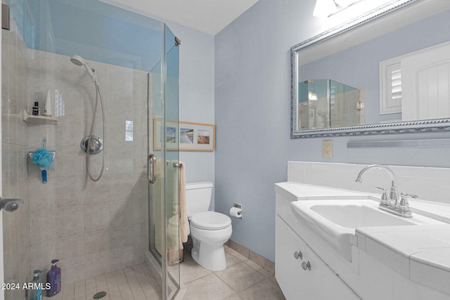 bathroom with tile patterned floors, vanity, toilet, and a shower with door