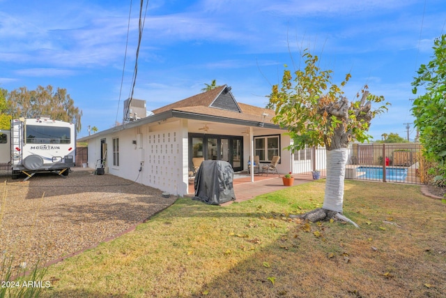 rear view of house with ceiling fan, a yard, and a patio