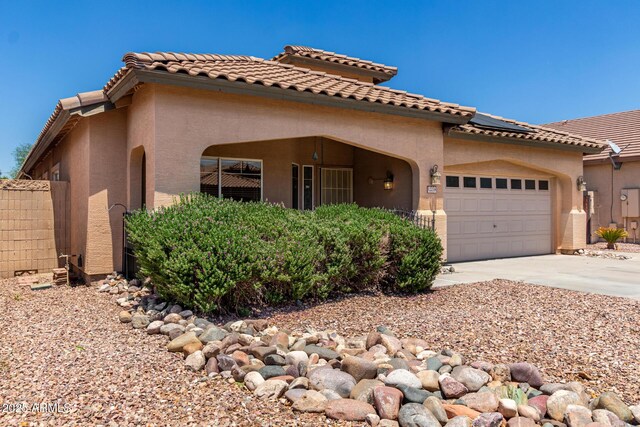 12238 W Monroe St, Avondale, AZ 85323 - mediterranean / spanish-style home with an attached garage, roof mounted solar panels, stucco siding, driveway, and a tile roof