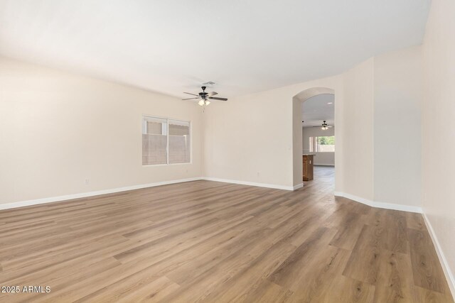 12238 W Monroe St, Avondale, AZ 85323 - unfurnished room with a ceiling fan, light wood-style floors, arched walkways, and baseboards