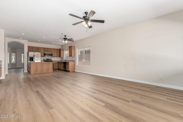 12238 W Monroe St, Avondale, AZ 85323 - unfurnished living room with arched walkways, baseboards, a ceiling fan, light wood-type flooring, and recessed lighting