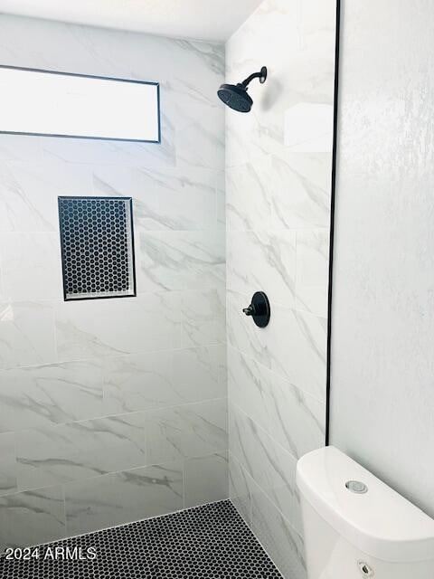 bathroom with toilet and a tile shower