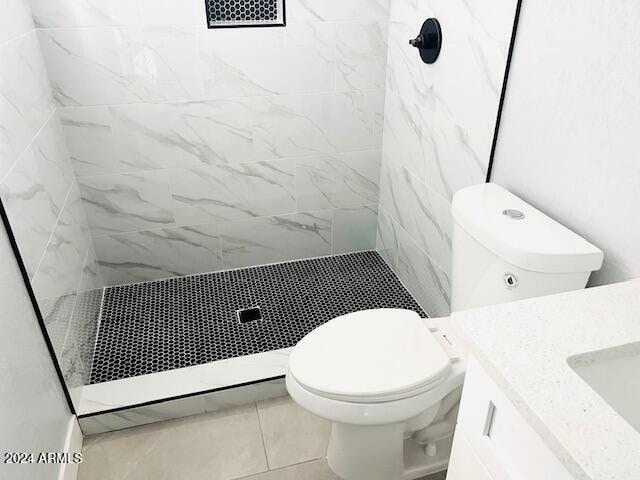 bathroom featuring toilet, tile patterned floors, and a tile shower