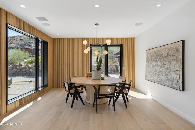 dining space with wooden walls and light hardwood / wood-style floors