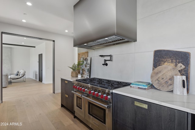 kitchen featuring range with two ovens, light hardwood / wood-style flooring, and exhaust hood