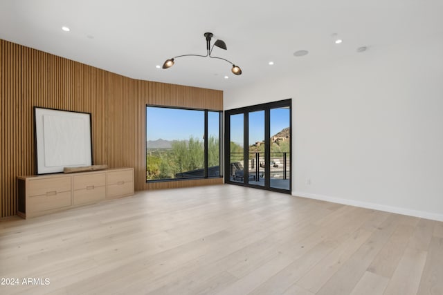 unfurnished living room featuring light hardwood / wood-style floors and wooden walls