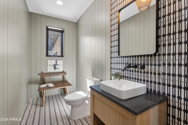 bathroom featuring vanity, toilet, wooden walls, and tile patterned flooring