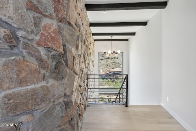 hallway featuring light wood-type flooring, beamed ceiling, and a notable chandelier