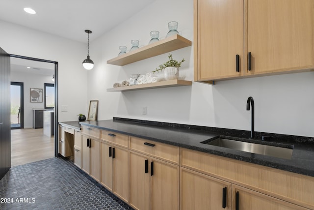 kitchen with decorative light fixtures, dark hardwood / wood-style flooring, dark stone countertops, light brown cabinetry, and sink