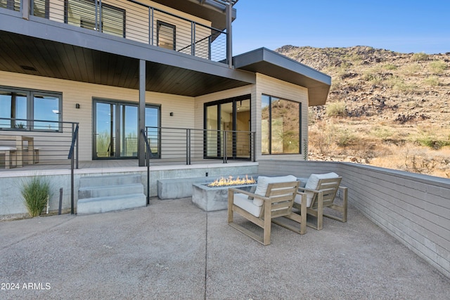 view of patio with a mountain view, a fire pit, and a balcony