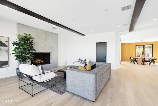 living room with wood walls, light hardwood / wood-style floors, beam ceiling, and a fireplace