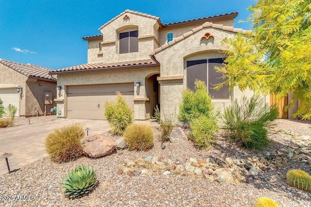 mediterranean / spanish house featuring a tiled roof, decorative driveway, and stucco siding