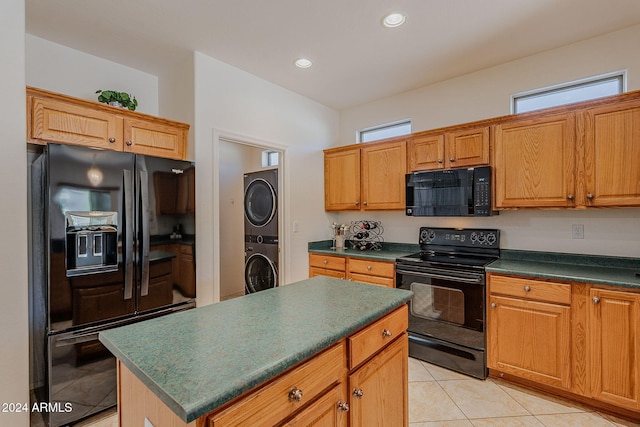 kitchen featuring black appliances, a center island, light tile patterned floors, and stacked washer and dryer