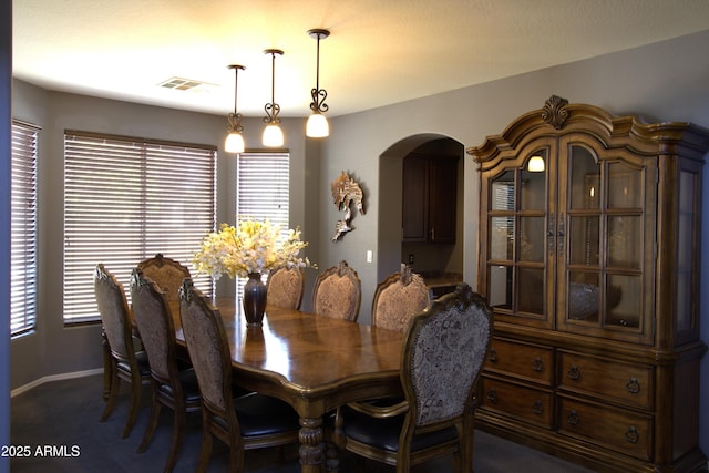 8920 S 40th Ln, Laveen, AZ 85339 - dining space featuring arched walkways, dark colored carpet, and baseboards