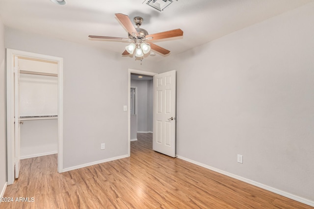 unfurnished bedroom with a closet, a walk in closet, light hardwood / wood-style floors, and ceiling fan