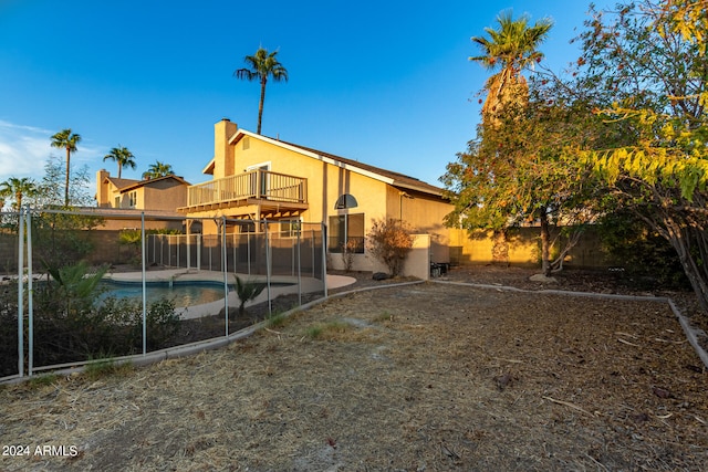 rear view of house with a fenced in pool, a patio area, and a balcony