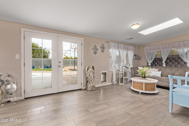 living room with lofted ceiling with skylight and french doors