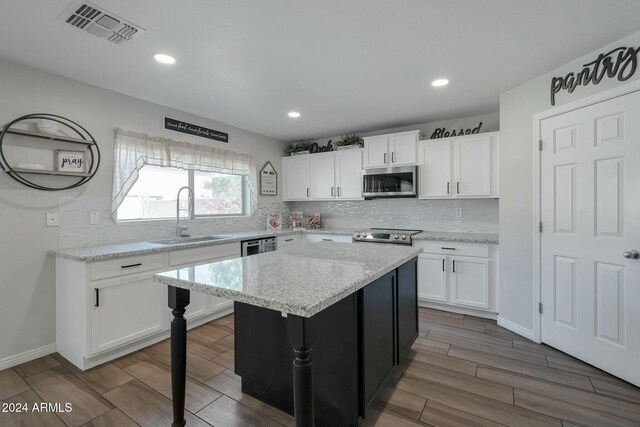 962 W Lindbergh Ave, Coolidge, AZ 85128 - kitchen featuring a center island, white cabinets, sink, wood-type flooring, and stainless steel appliances