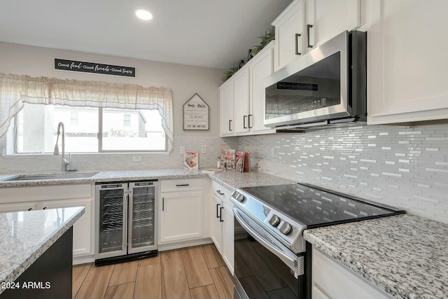 962 W Lindbergh Ave, Coolidge, AZ 85128 - kitchen with light stone countertops, stainless steel appliances, beverage cooler, sink, and white cabinetry