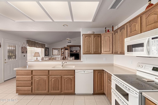 kitchen featuring light tile patterned flooring, lofted ceiling, sink, kitchen peninsula, and white appliances