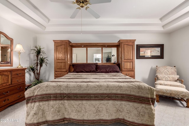 carpeted bedroom featuring a raised ceiling and ceiling fan