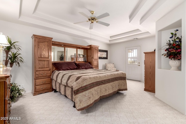 bedroom featuring light carpet, ceiling fan, and a tray ceiling