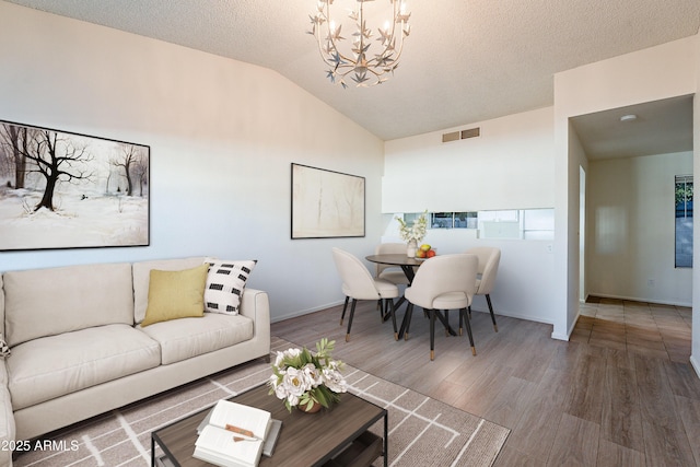 living room with vaulted ceiling, an inviting chandelier, a textured ceiling, and hardwood / wood-style flooring