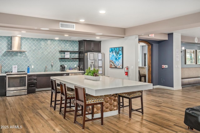 2511 W Queen Creek Rd Unit 378, Chandler, AZ 85248 - kitchen featuring a kitchen bar, wall chimney exhaust hood, stainless steel appliances, visible vents, and light countertops