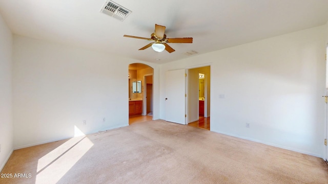 unfurnished room with arched walkways, visible vents, light carpet, and a ceiling fan