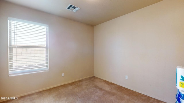 carpeted spare room with visible vents and baseboards